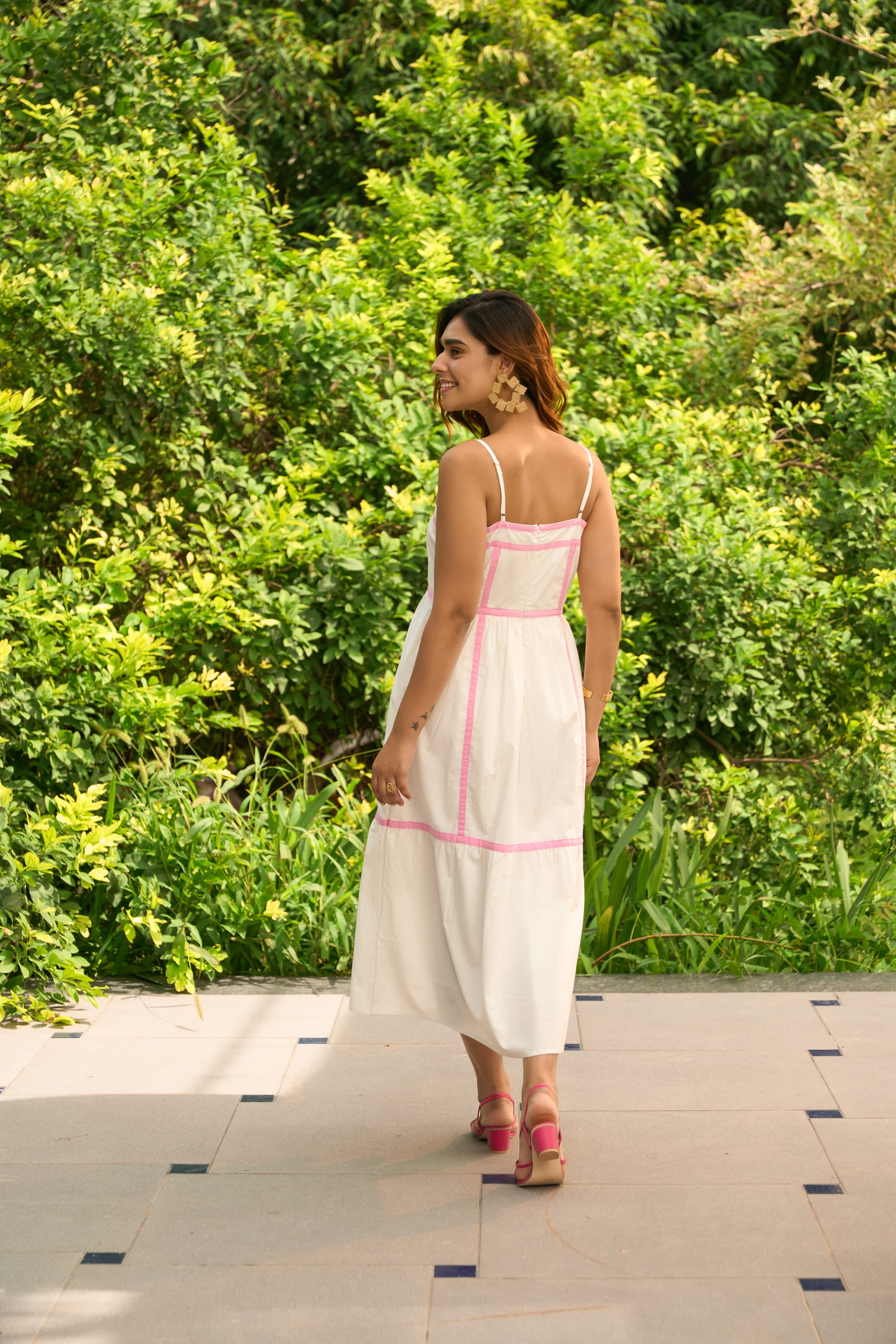Woman wearing Amalfi dress with pink trim walking outdoors on tiled pavement