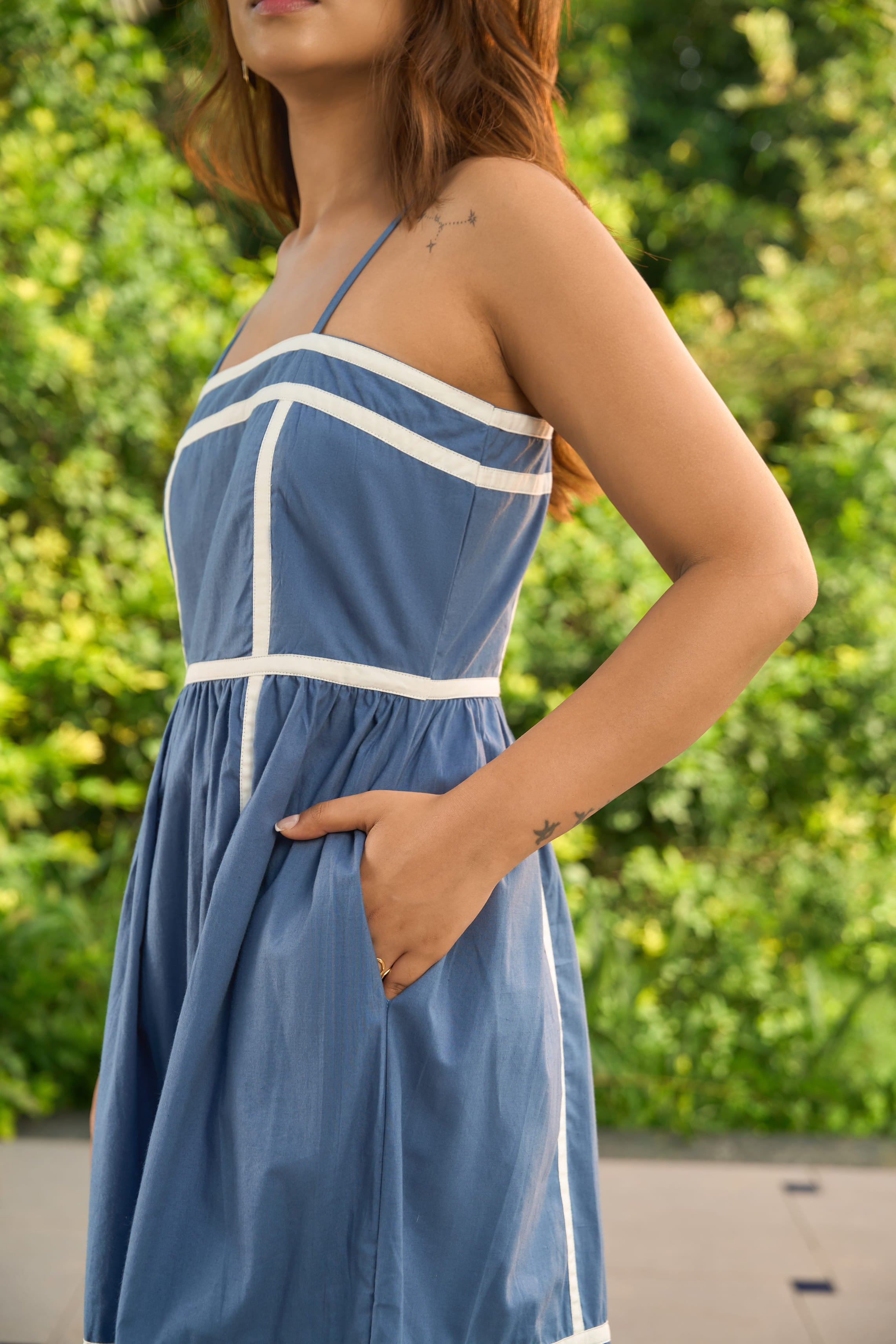 Woman wearing Santorini blue sundress with white trim and spaghetti straps outdoors
